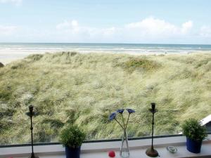 ブロックフスにある6 person holiday home in Blokhusの植物のある窓からビーチの景色を望めます。