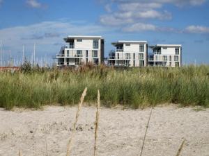 two houses on top of a beach with tall grass at 8 person holiday home in Wendtorf in Wendtorf