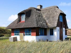 a house with a thatched roof in a field at 5 person holiday home in Ulfborg in Fjand Gårde