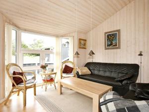 Øster Hurupにある8 person holiday home in Hadsundのリビングルーム(黒いソファ、テーブル付)