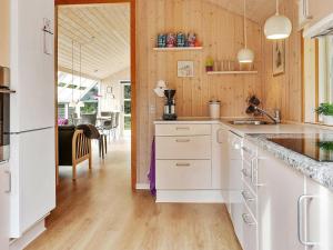 ヘンネ・ストランドにある6 person holiday home in Henneの白いキャビネットと木製の壁が備わるキッチン