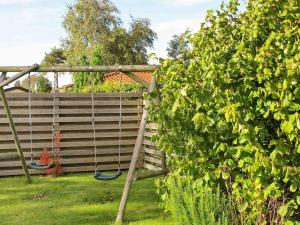 a swing in a garden next to a fence at 6 person holiday home in Str by in Strøby