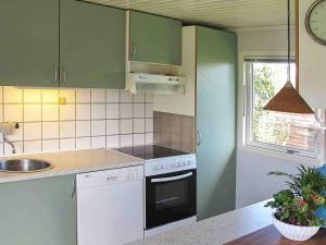 een keuken met groene en witte apparatuur en een raam bij 6 person holiday home in Str by in Strøby