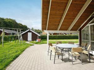 a patio with a table and chairs and a swing at 8 person holiday home in Juelsminde in Sønderby