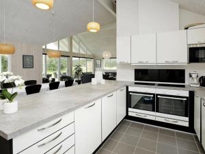 une cuisine avec des placards blancs et un salon dans l'établissement 18 person holiday home in Bl vand, à Blåvand
