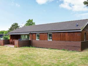 a wooden house with a deck in a yard at Two-Bedroom Holiday home in Ringkøbing 10 in Dannemare