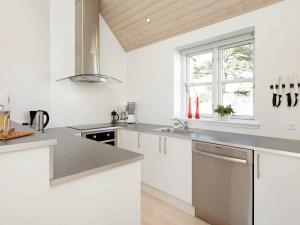 ヒアツハルスにある6 person holiday home in Hirtshalsの白いキャビネットと窓付きの白いキッチン
