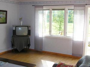 a living room with a tv and two windows at 6 person holiday home in H CKSVIK in Håcksvik