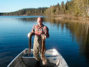 a man standing in a boat holding a large fish at 6 person holiday home in H CKSVIK in Håcksvik