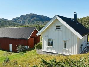 una casa blanca y un granero rojo en una colina en Holiday Home Grendaveien, en Oksvoll