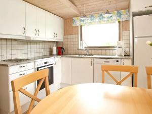 Fjerritslevにある8 person holiday home in Fjerritslevの白いキャビネット、テーブルと椅子付きのキッチンが備わります。
