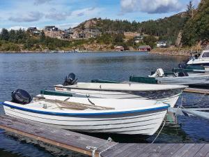 tres barcos atracados en un muelle en un lago en 5 person holiday home in lyngdal, en Korshamn