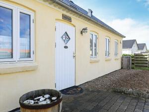 a building with a white door and a trash can at 6 person holiday home in Harbo re in Harboør