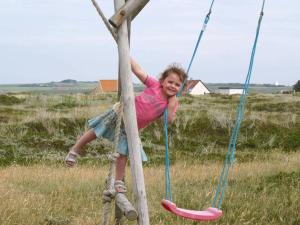 a young girl is playing on a swing at 6 person holiday home in Harbo re in Harboør