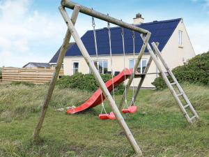 a swing set in a yard in front of a house at 6 person holiday home in Harbo re in Harboør