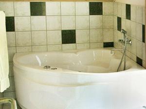 a white tub in a bathroom with a tiled wall at 6 person holiday home in Dannemare in Dannemare