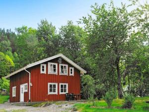Casa roja con ventanas blancas y mesa en Four-Bedroom Holiday home in S-Uddvalla, en Ljungskile