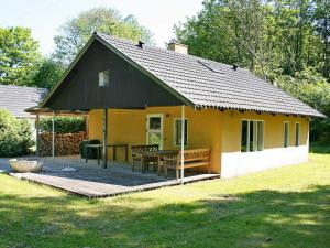 uma pequena casa amarela com um deque de madeira em 6 person holiday home in Aakirkeby em Åkirkeby
