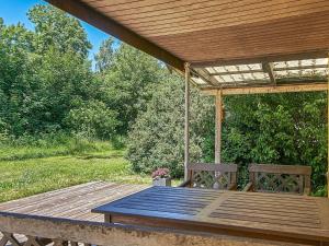 uma mesa de madeira e dois bancos sob uma pérgola de madeira em 6 person holiday home in Aakirkeby em Åkirkeby