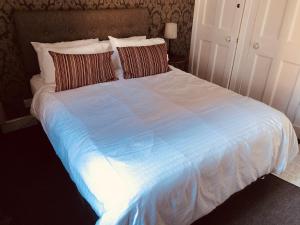 1 cama grande con sábanas y almohadas blancas en Edinburgh Old Town Apartment en Edimburgo