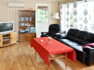 a living room with a black leather couch and a table at Two-Bedroom Holiday home in Vågland 4 in Rabben