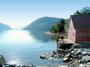 a red building next to a body of water at 4 person holiday home in Lauvstad-By Traum in Lauvstad