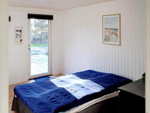 a bedroom with a blue bed and a window at 8 person holiday home in R dby in Kramnitse