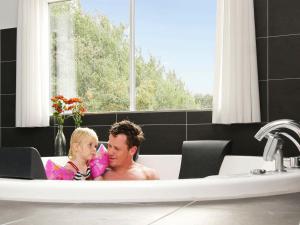 un uomo e un bambino seduti in una vasca da bagno di 20 person holiday home in Sydals a Høruphav