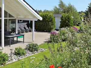 a patio with a table and chairs in a garden at 12 person holiday home in Idestrup in Marielyst