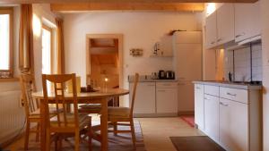 a kitchen with a table and chairs and a kitchen with a refrigerator at Appartements Sonngarten in Campo Tures
