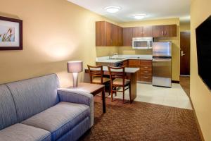 a living room with a couch and a table and a kitchen at Microtel Inn & Suites by Wyndham Red Deer in Red Deer