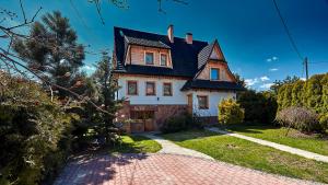 a house with a black roof and a brick driveway at Willa Pod Ściętą Lipą in Ząb