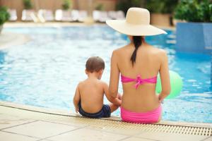 a woman and a child sitting next to a swimming pool at Villa L'Auberge in San Diego