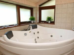8 person holiday home in Fjerritslev في Torup Strand: حوض استحمام أبيض في حمام به نوافذ