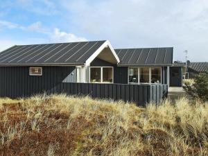 a black house on top of a hill at 10 person holiday home in Harbo re in Harboør
