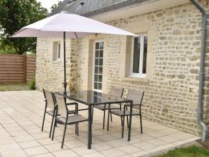a table with chairs and an umbrella on a patio at Cozy Cottage in Fresville with Garden in Fresville