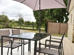 a table and chairs with an umbrella on a patio at Cozy Cottage in Fresville with Garden in Fresville