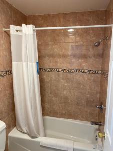 a bathroom with a shower with a white shower curtain at Golden West Manor Motel in Los Angeles