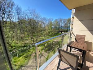 a balcony with a bench and a view of the woods at Diune Resort & Apartamenty in Kołobrzeg