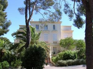 サン・ラファエルにあるApartment in villa with pool and beach accessの目の前に木々が植えられた白い大きな建物