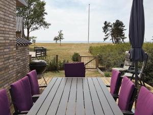 a wooden table with purple chairs and an umbrella at 7 person holiday home in Sydals in Kegnæshøj