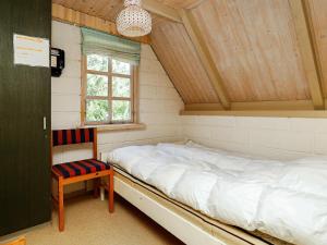 a bed in a room with a window and a chair at Holiday Home Fyrrealle in Nørby