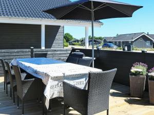 Hadsundにある8 person holiday home in Hadsundのパティオ(パラソル付きのテーブルと椅子付)