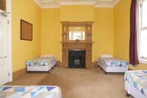 a yellow room with two beds and a fireplace at Verandahs Parkside Lodge in Auckland