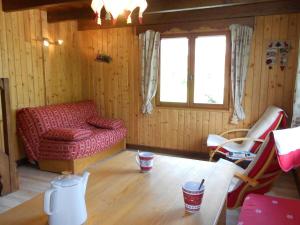 a living room with a red couch and a table at Cosy chalet with garden in Notre-Dame-de-Bellecombe