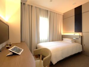 a hotel room with a bed and a desk with a chair at Hotel Nikko Narita in Narita