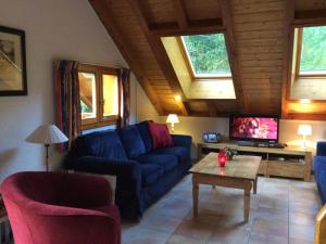 a living room with a blue couch and a tv at Mountain Chalet in Oz en Oisans with Lovely Views over Lake in Oz