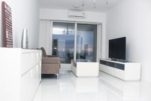 sala de estar blanca con TV y sofá en Azure Punta Executive, en Punta del Este