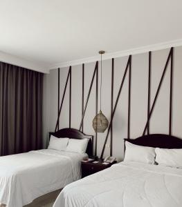 two beds in a hotel room with white sheets at Hotel Mirador Plaza in San Salvador