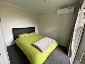 a bedroom with a green bed in a room at Comfortable Home Close to Airport in Christchurch